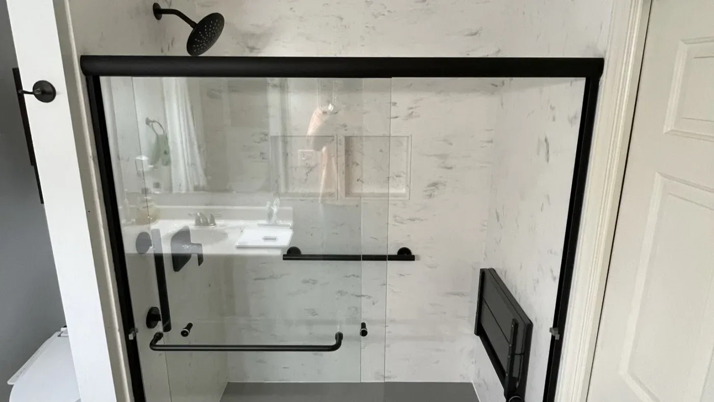 New walk-in shower install with sliding glass door and beautiful marble-styled surround.