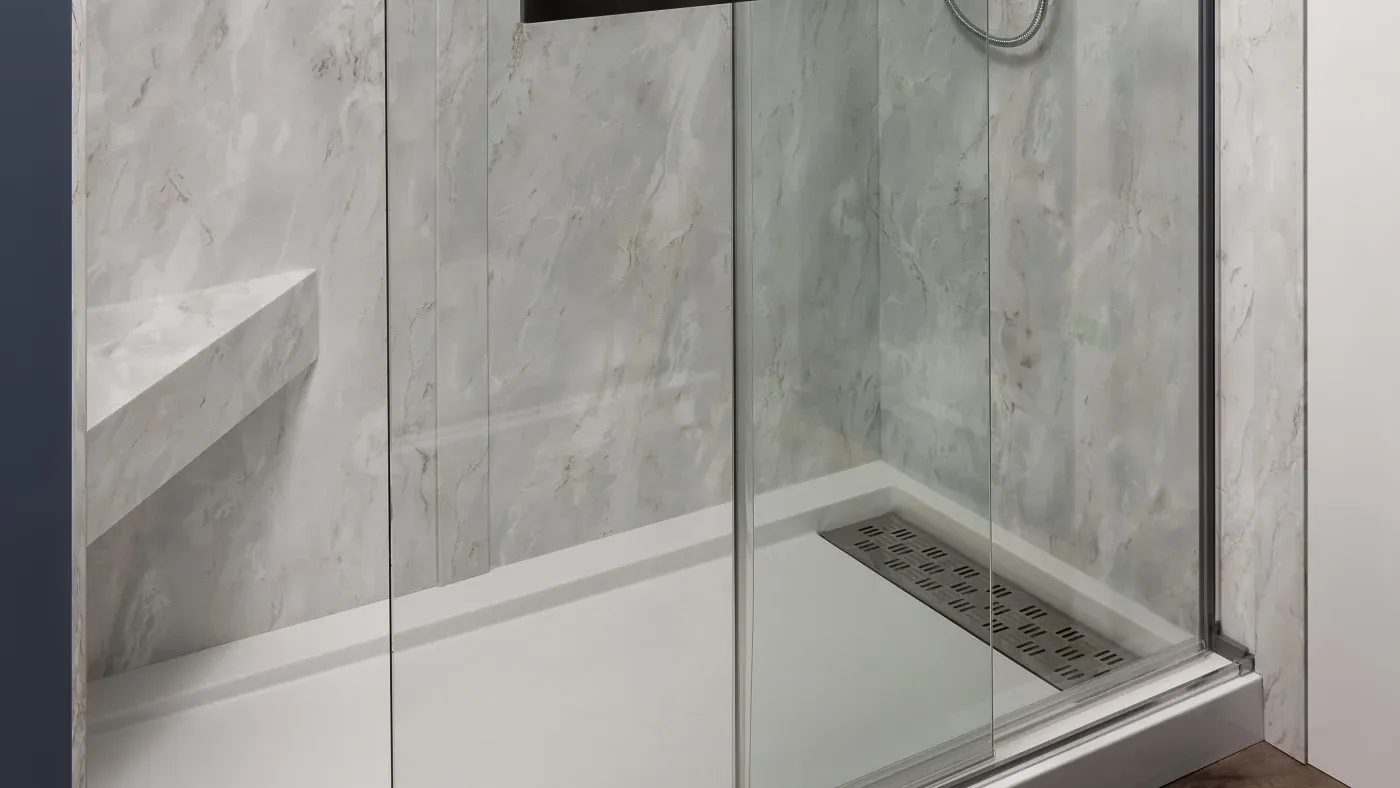 Base of new shower with sliding glass door and marble-styled surround.