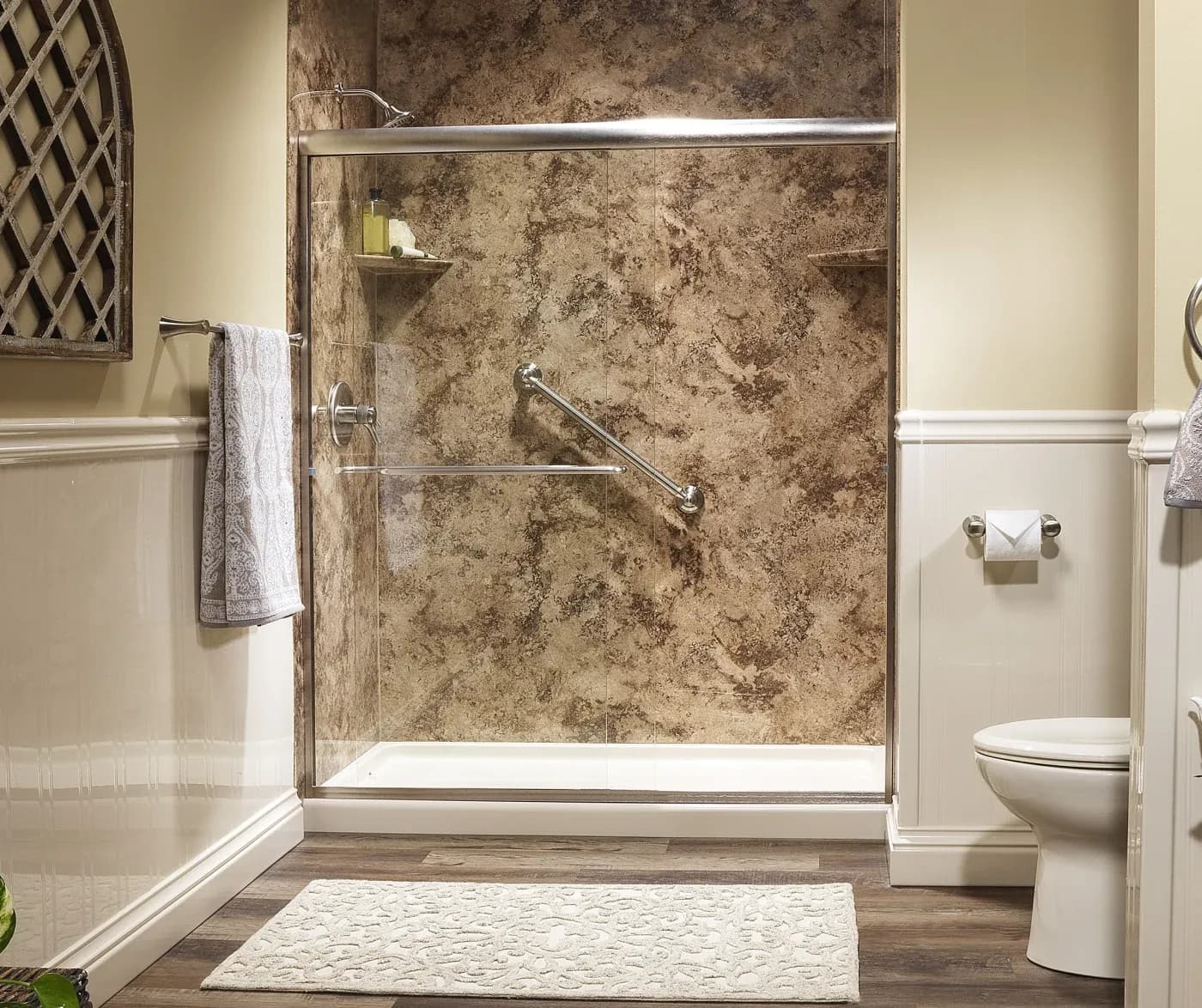 A walk-in shower with a brown textured stall, a grab bar, and sliding glass doors.