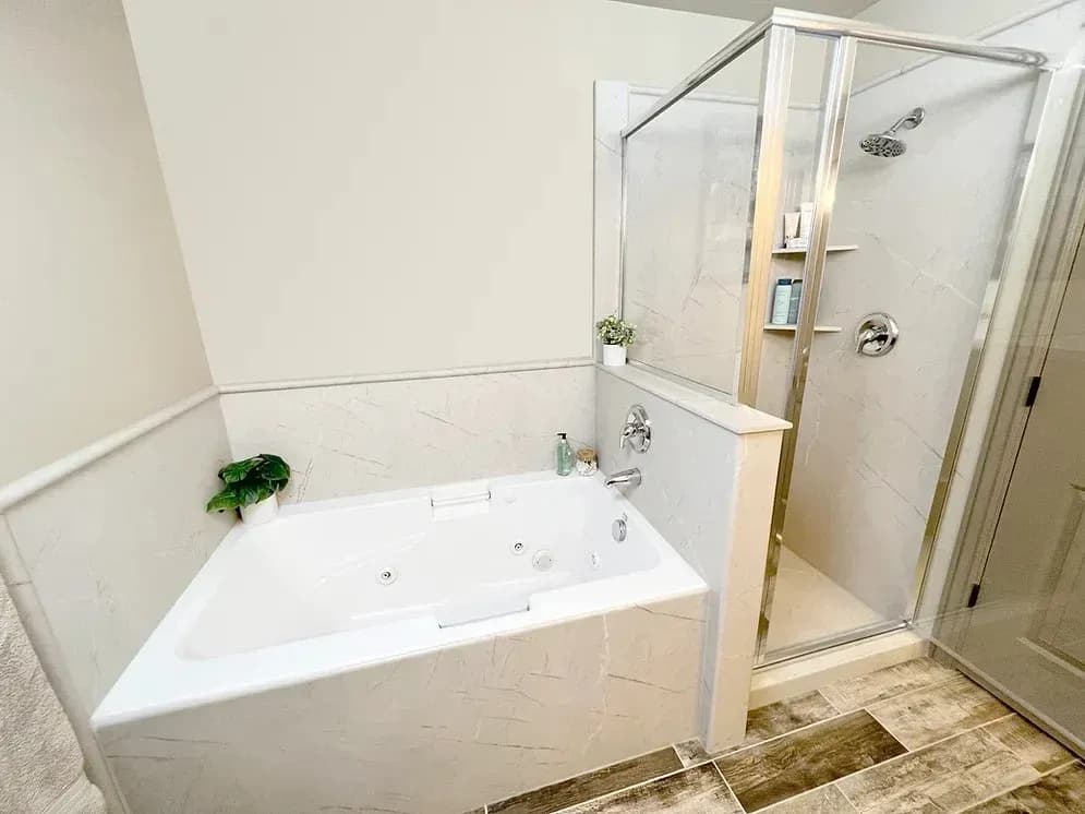 A newly remodeled residential bathroom in NW Arkansas with a luxurious new bathtub and small compact walk-in shower with new hardware and glass doors.