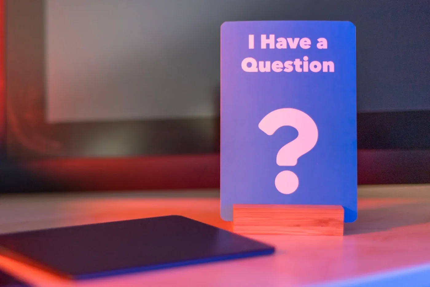 A card standing up by a laptop with the words “I Have A Question” on it, signifying FAQs.